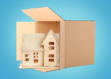 Image of Wooden model of house in cardboard box on turquoise background