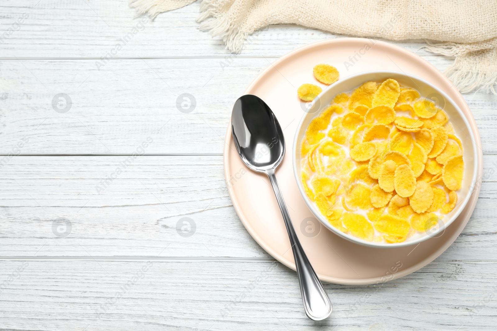 Photo of Tasty corn flakes with milk on white wooden table, flat lay. Space for text