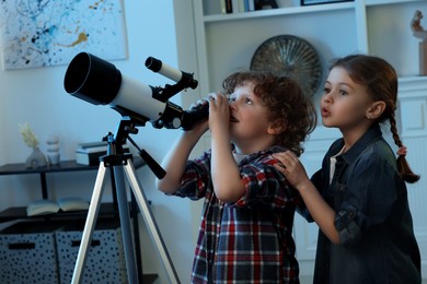 Cute little children using telescope to look at stars in room