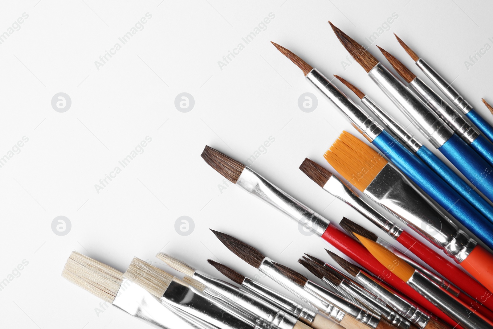 Photo of Different paint brushes on white background, top view. Space for text