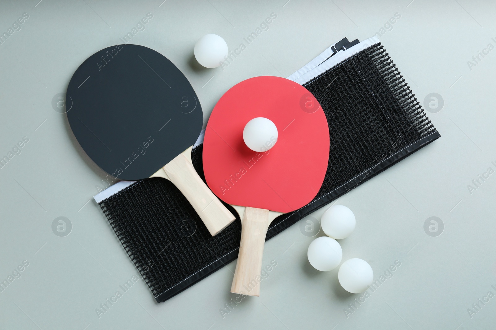 Photo of Ping pong rackets, net and balls on grey background, flat lay