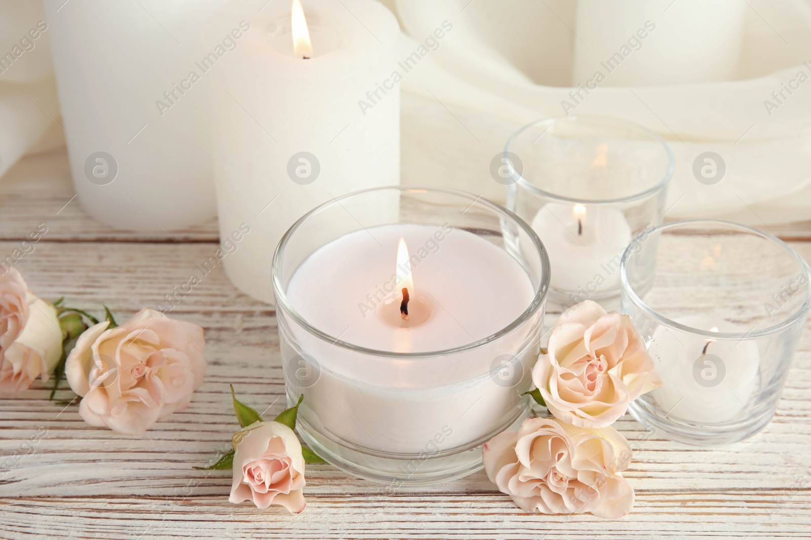 Photo of Composition with burning aromatic candles and roses on wooden table