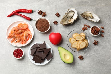 Natural aphrodisiac. Different food products and heart model on grey table, flat lay