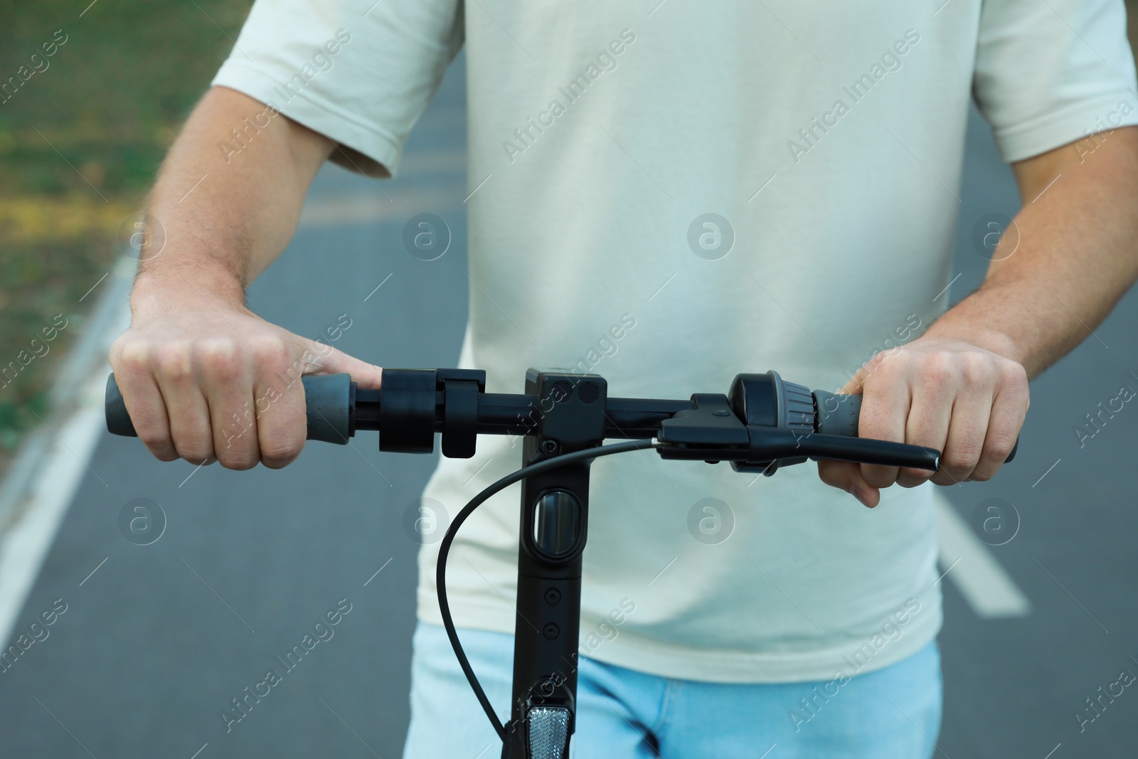 Photo of Man riding modern electric kick scooter outdoors, closeup