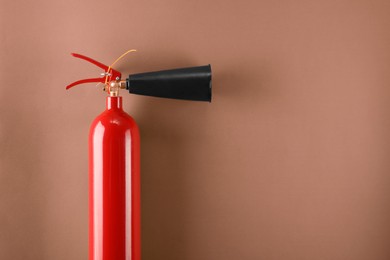 Photo of Fire extinguisher on light brown background, top view. Space for text