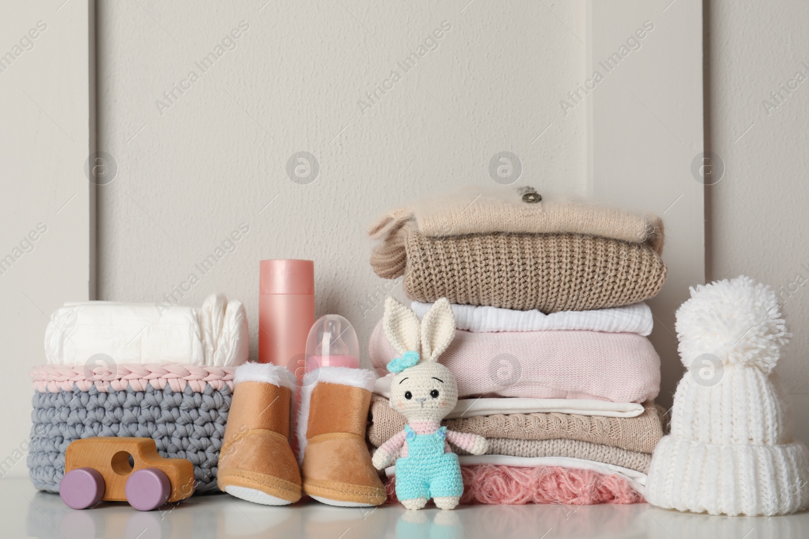 Photo of Baby clothes, toys and accessories on white table