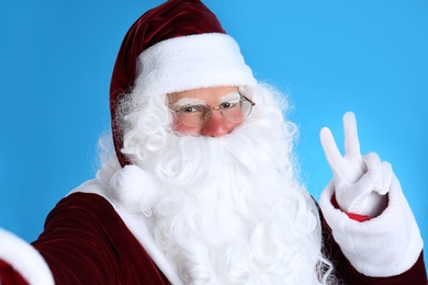 Photo of Santa Claus taking selfie on light blue background