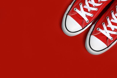 Photo of Pair of new stylish sneakers on red background, flat lay. Space for text