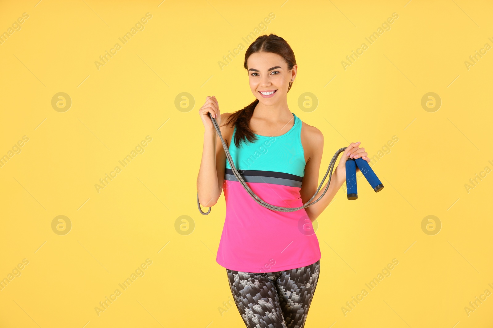 Photo of Portrait of young sportive woman with jump rope on color background