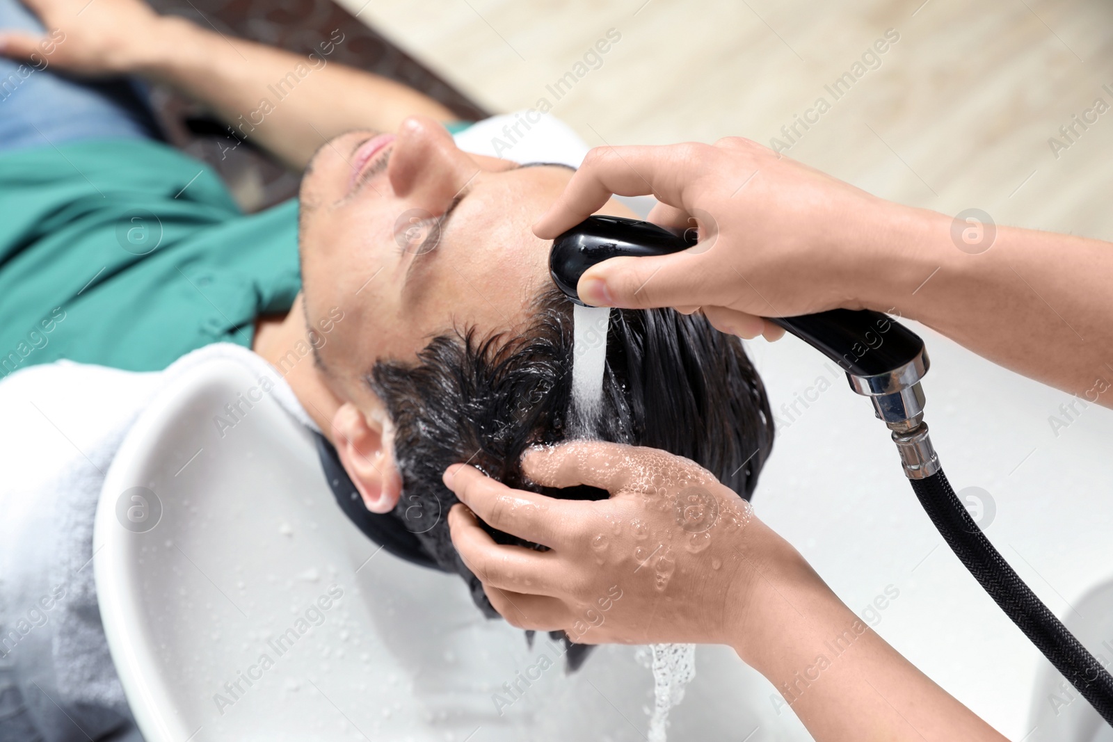 Photo of Stylist washing client's hair at sink in beauty salon