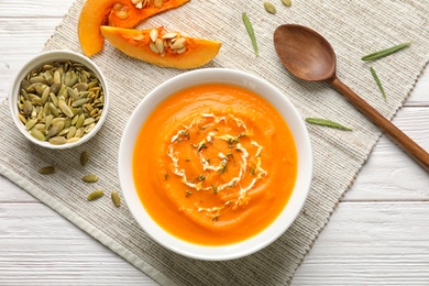 Photo of Flat lay composition with bowl of pumpkin soup on wooden table