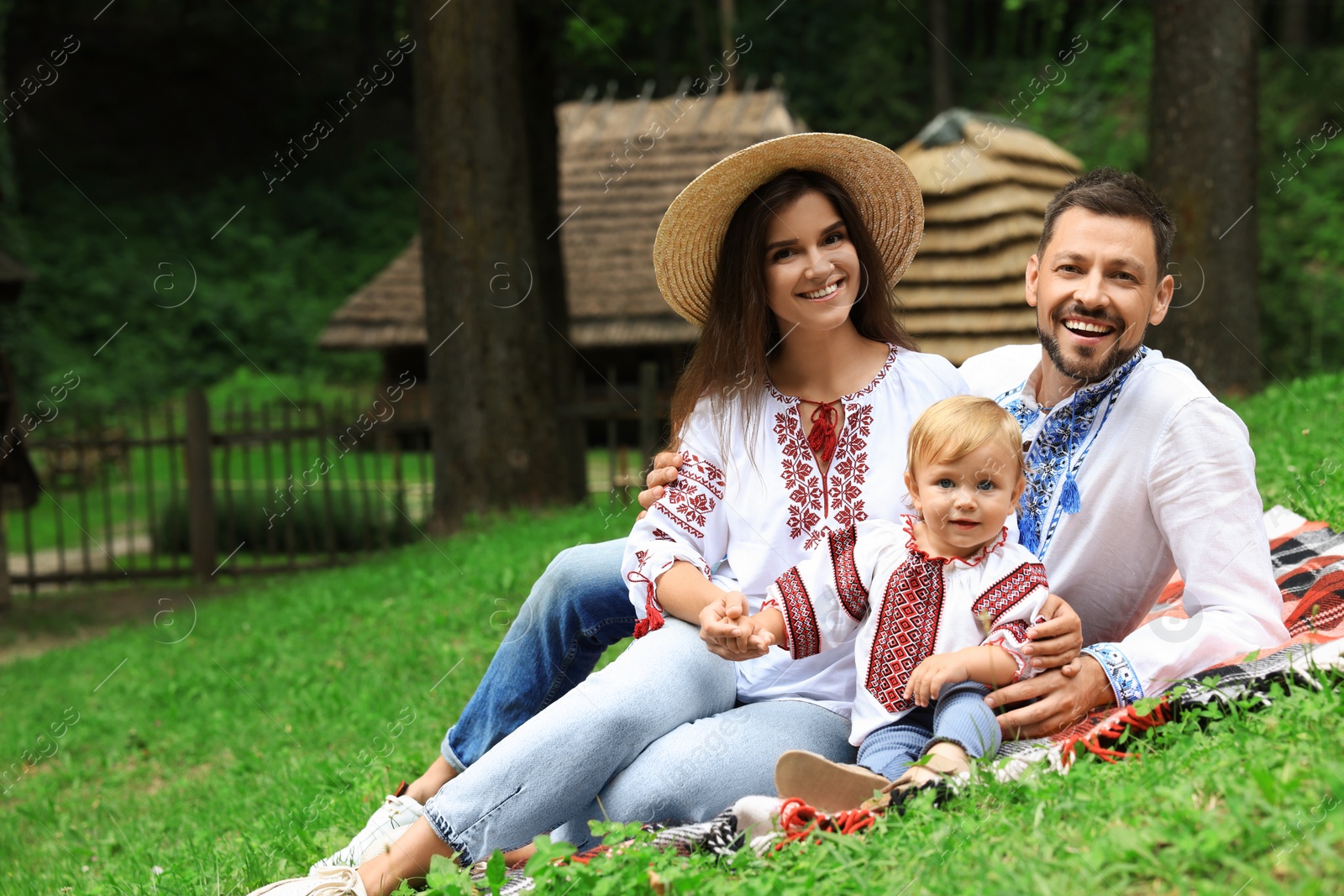 Photo of Happy family in Ukrainian national clothes on green grass outdoors