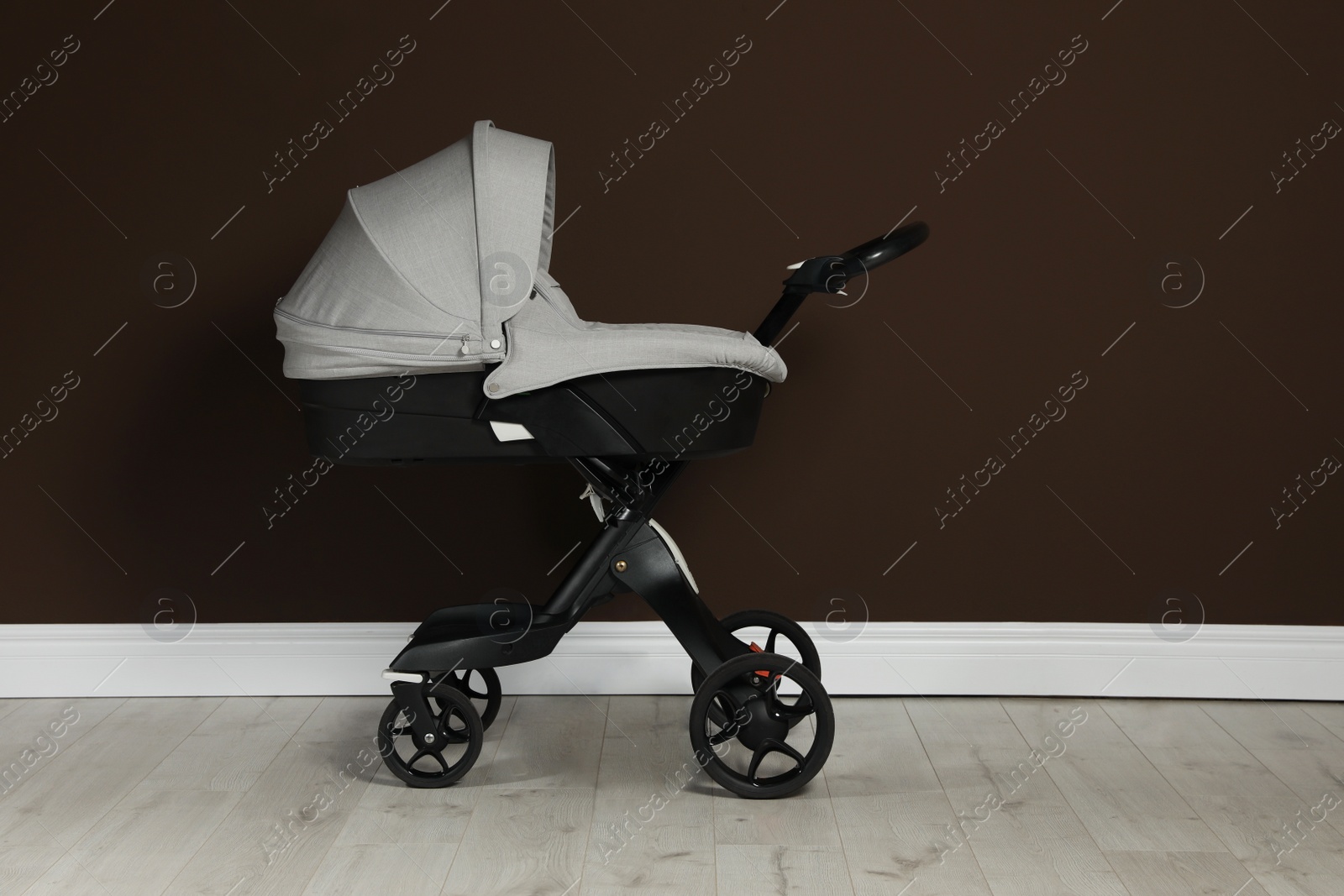 Photo of Baby carriage. Modern pram near brown wall