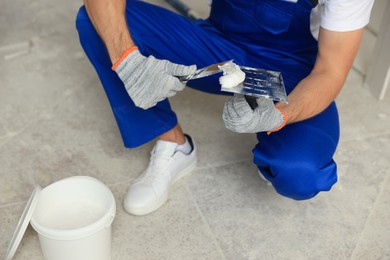 Worker with putty knife putting plaster on float, closeup