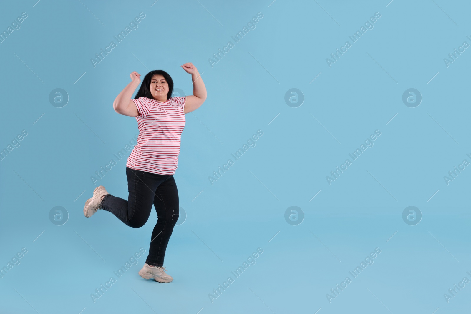 Photo of Beautiful overweight mature woman jumping on turquoise background. Space for text