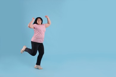 Photo of Beautiful overweight mature woman jumping on turquoise background. Space for text