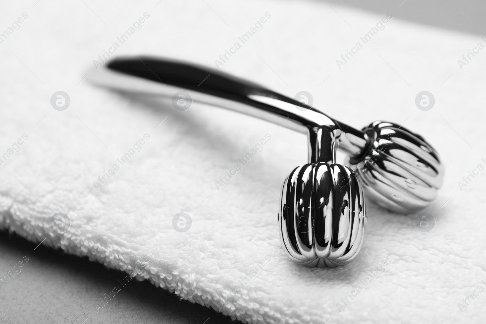 Photo of Metal face roller on white towel, closeup
