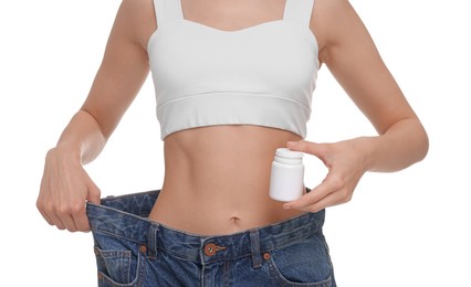 Photo of Slim woman in big jeans with bottle of pills on white background, closeup. Weight loss