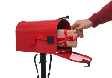 Photo of Man putting Christmas gift into mailbox on white background, closeup. Sending present by mail