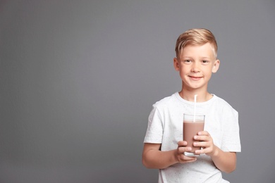 Photo of Little boy with glass of milk shake on grey background