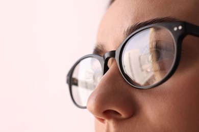 Photo of Woman wearing glasses on blurred background, closeup. Space for text