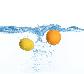Photo of Ripe orange and lemon falling down into clear water with splashes against white background
