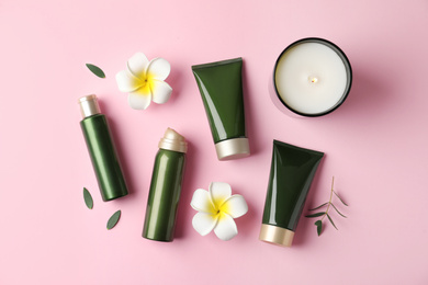 Flat lay composition with cosmetic products and tropical flowers on pink background