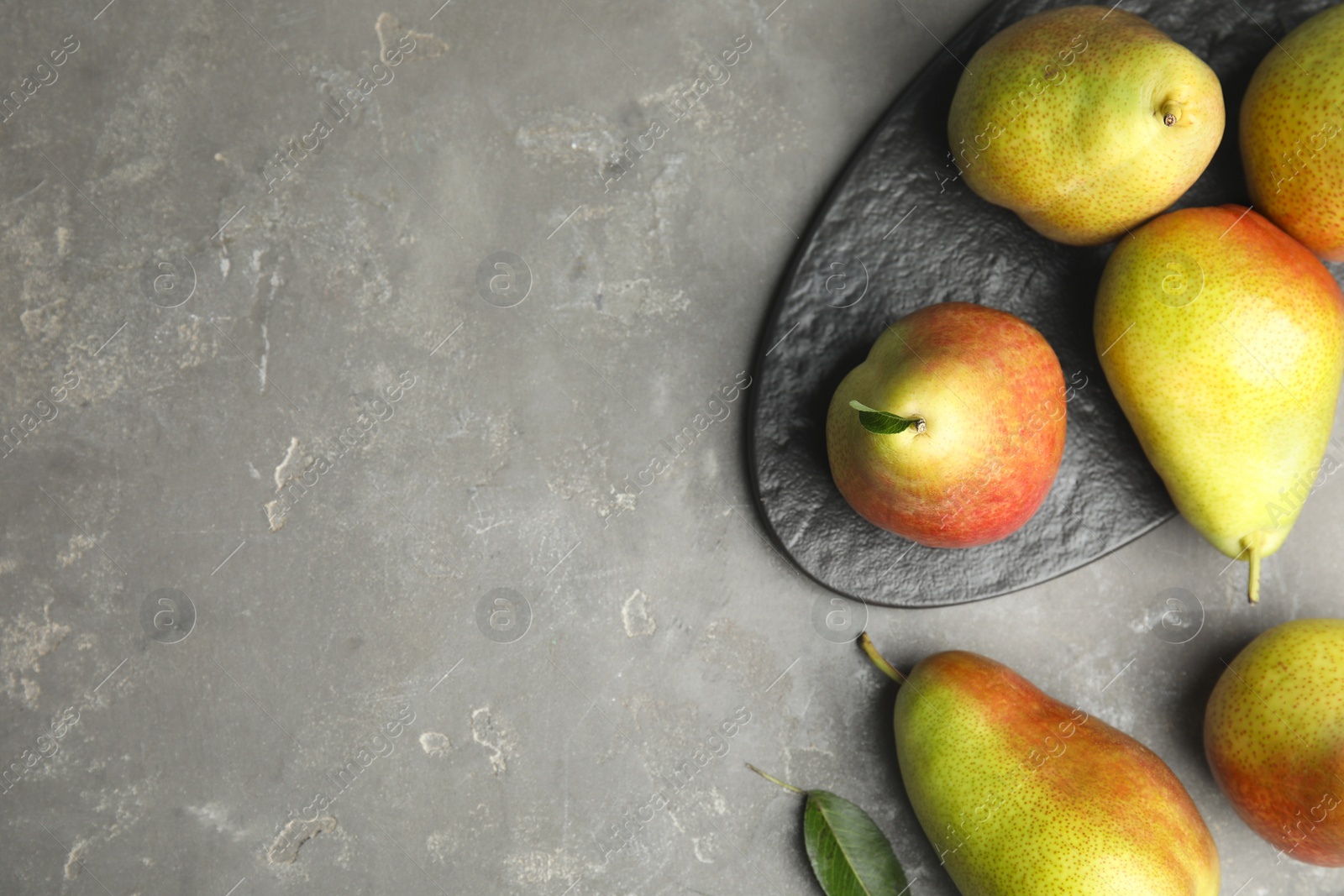 Photo of Ripe juicy pears on grey stone table, flat lay. Space for text