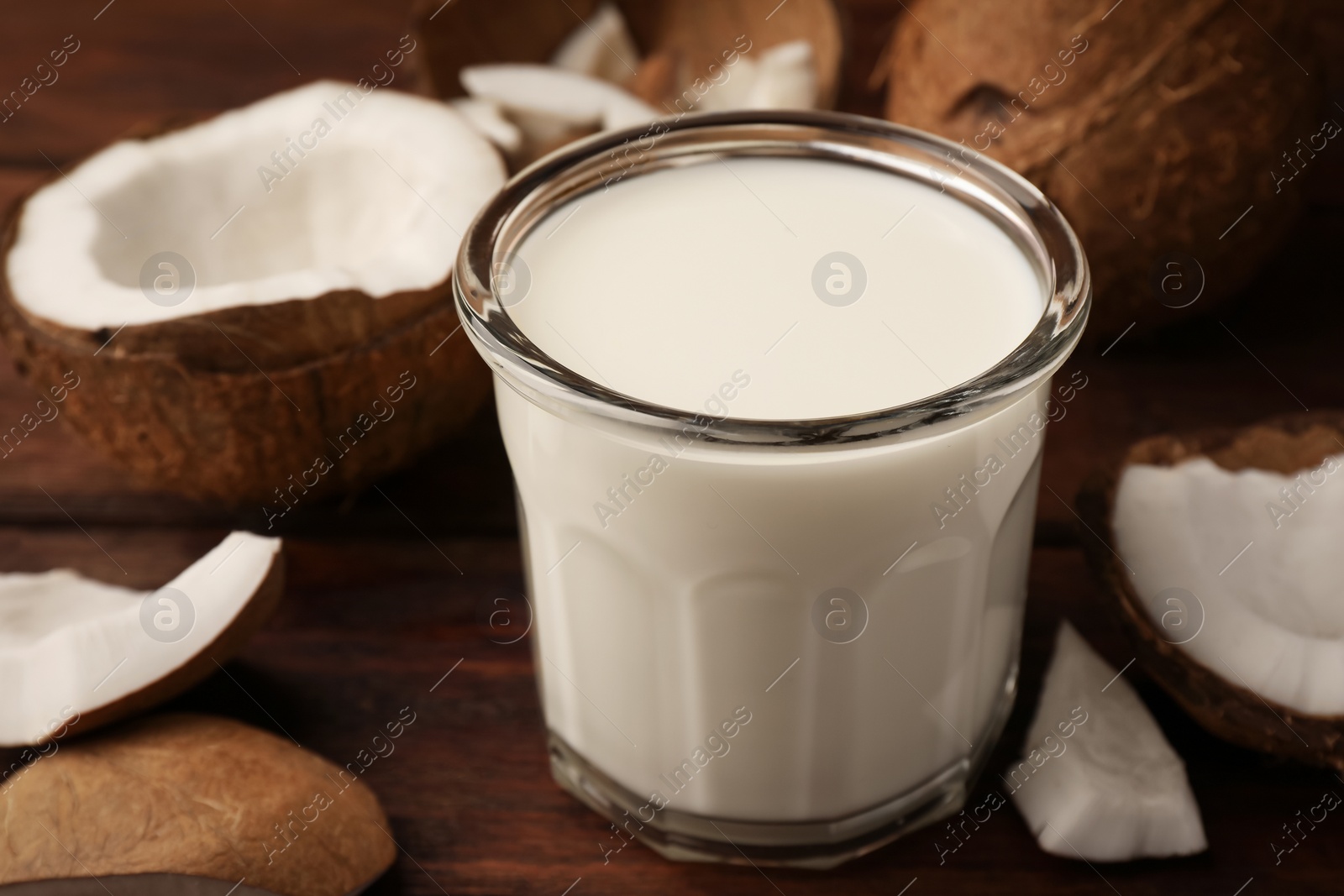 Photo of Glass of delicious vegan milk and coconut pieces on wooden table, closeup