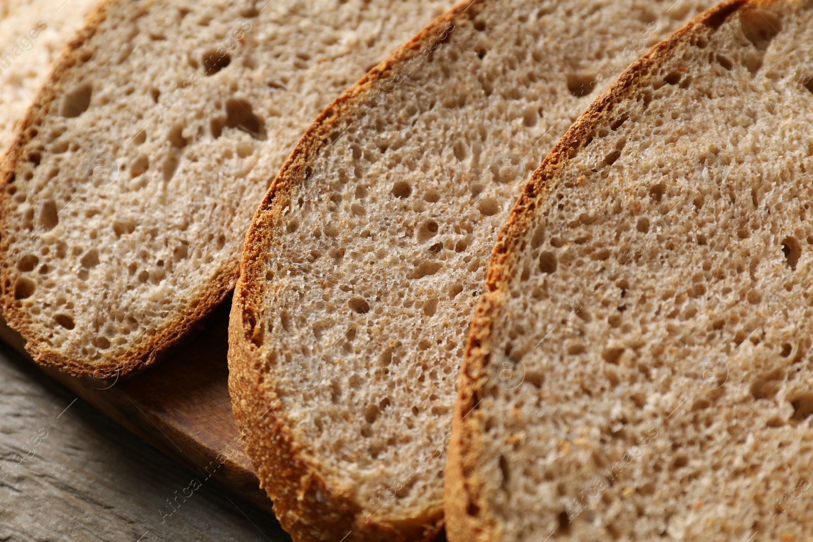 Photo of Freshly baked cut sourdough bread on wooden table, closeup