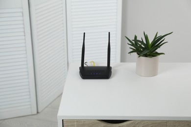 Photo of Modern Wi-Fi router on white table in room