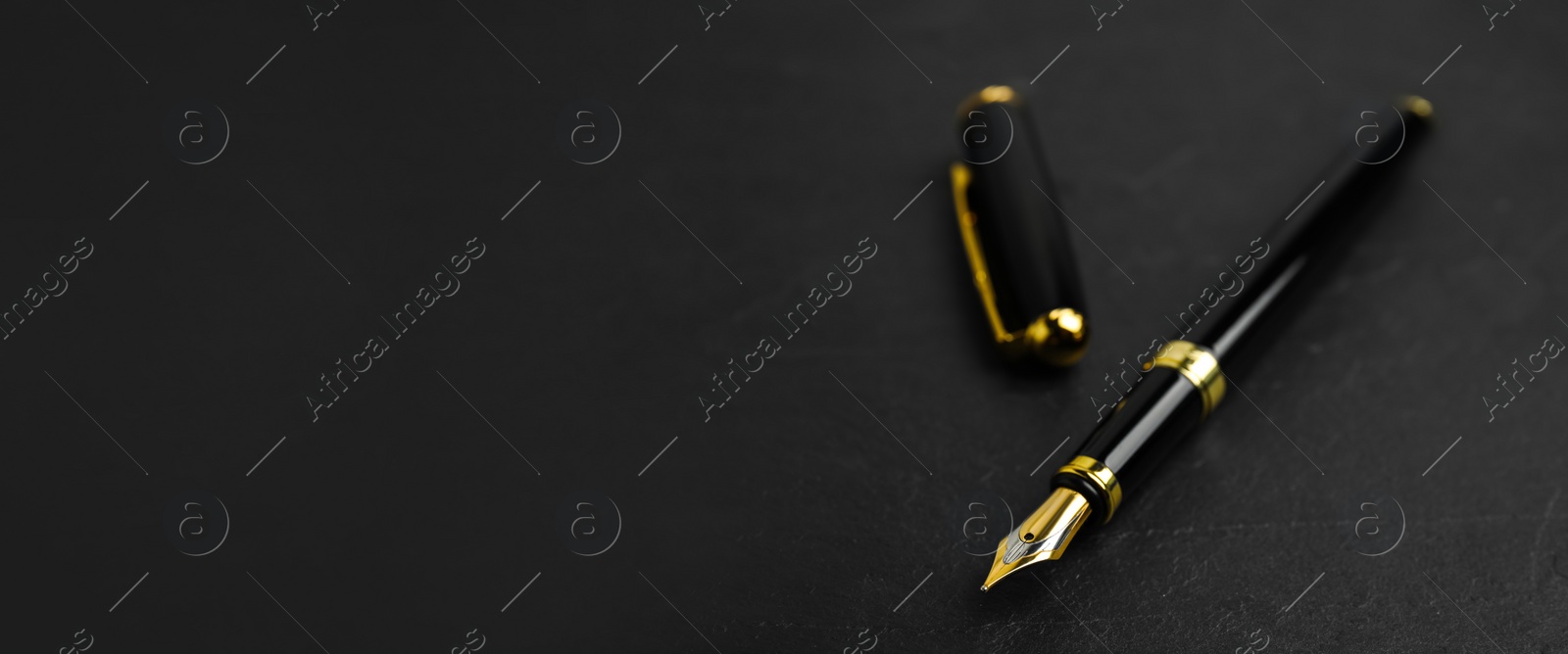 Image of Beautiful fountain pen with ornate nib on black table, closeup view with space for text. Banner design