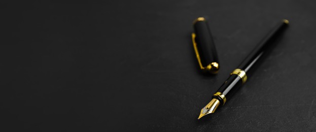 Beautiful fountain pen with ornate nib on black table, closeup view with space for text. Banner design