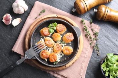 Photo of Delicious fried scallops in dish served on dark gray textured table, flat lay