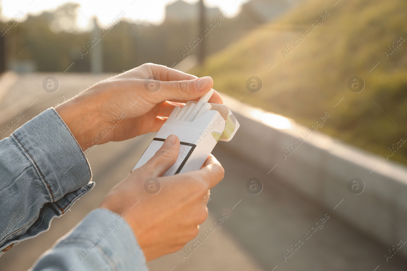 Photo of Woman taking cigarette out of pack outdoors, closeup. Space for text