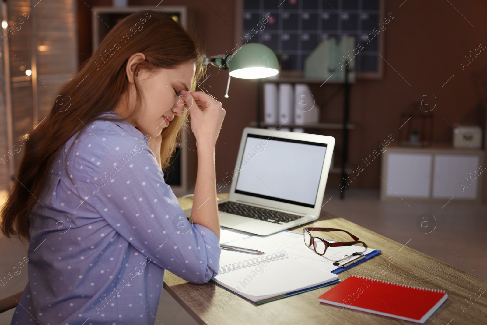 Photo of Overworked young woman with headache in office