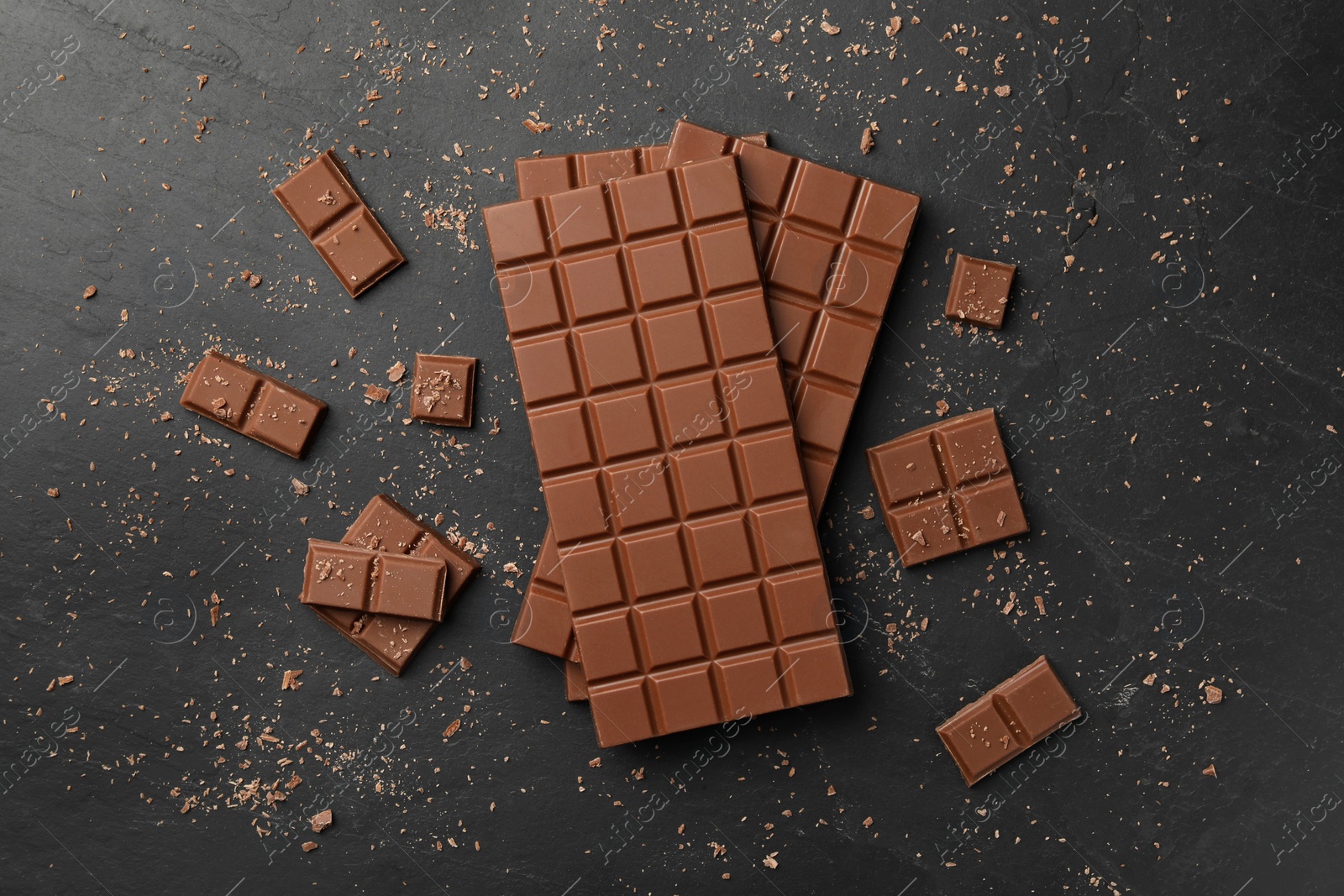 Photo of Pieces of tasty chocolate on grey table, flat lay