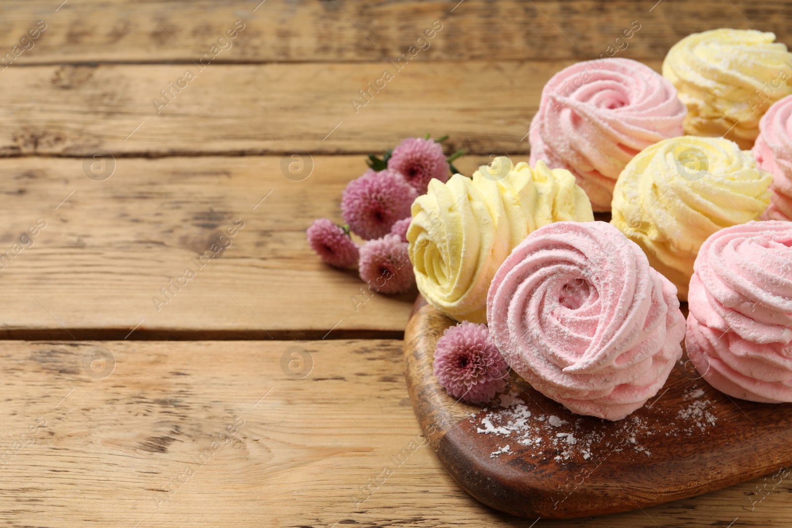 Photo of Delicious pink and yellow marshmallows on wooden table. Space for text