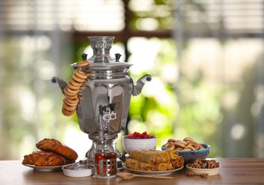 Image of Traditional Russian samovar and treats on wooden table against window in room