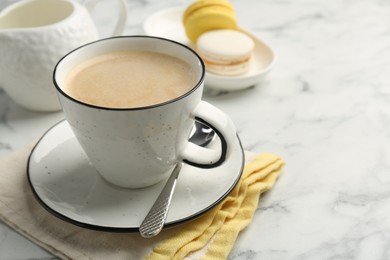 Photo of Tasty cappuccino in cup, spoon and saucer on white marble table, closeup. Space for text