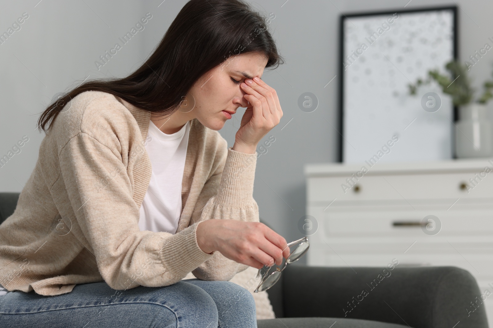 Photo of Overwhelmed woman sitting on sofa at home