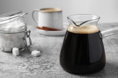 Photo of Turkish coffee in glass cezve on light grey table. Space for text