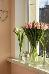 Photo of Bouquet of beautiful tulips in glass vase and spring flowers on windowsill indoors
