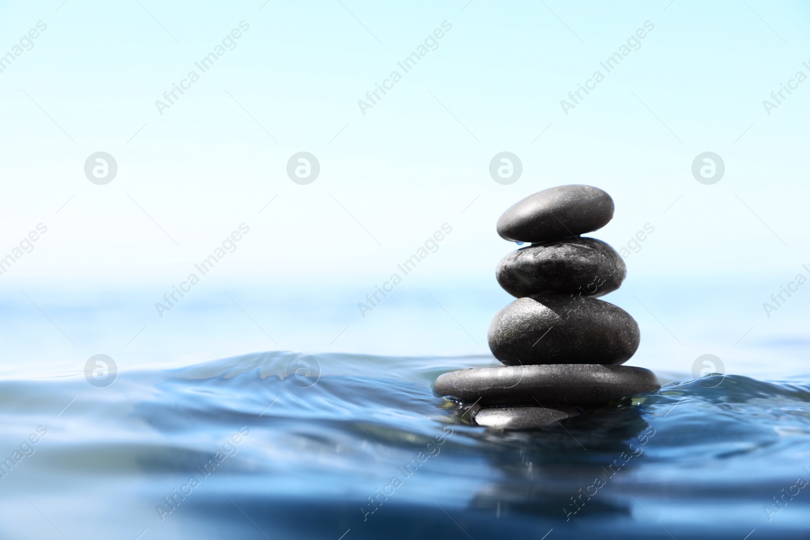 Photo of Stack of stones in sea water, space for text. Zen concept