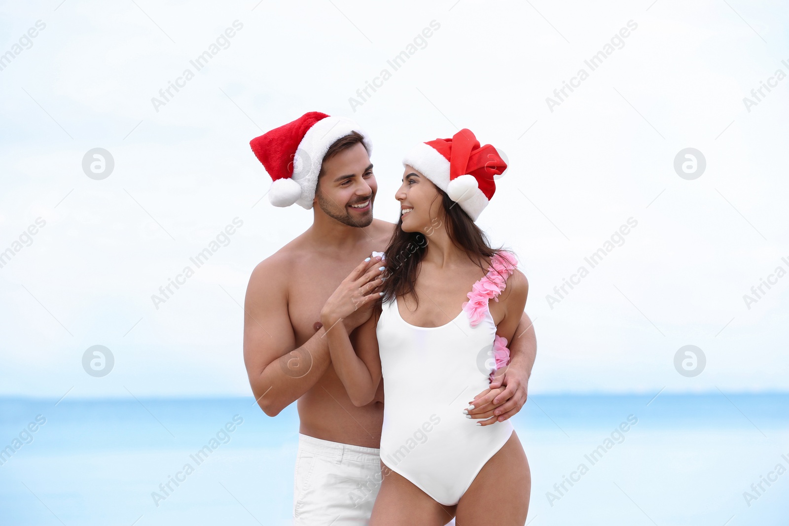 Photo of Happy young couple with Santa hats together on beach