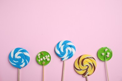 Photo of Sticks with different colorful lollipops on pink background, flat lay. Space for text