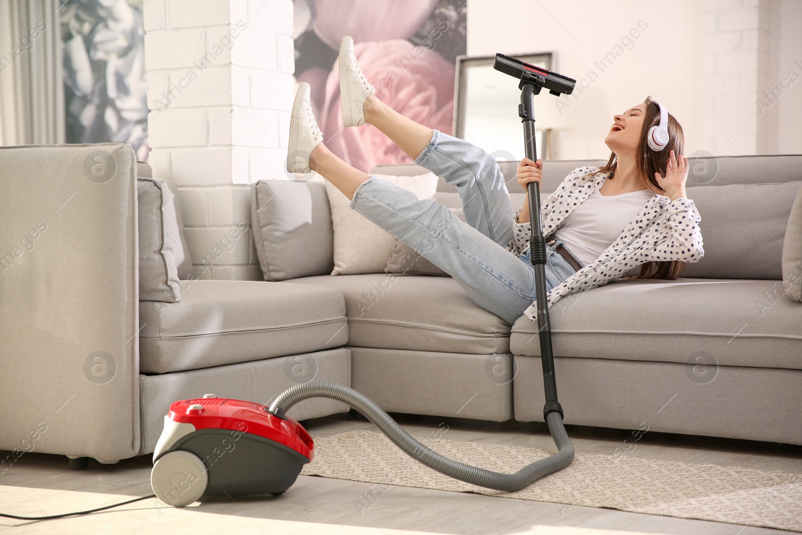 Photo of Young woman having fun while vacuuming at home