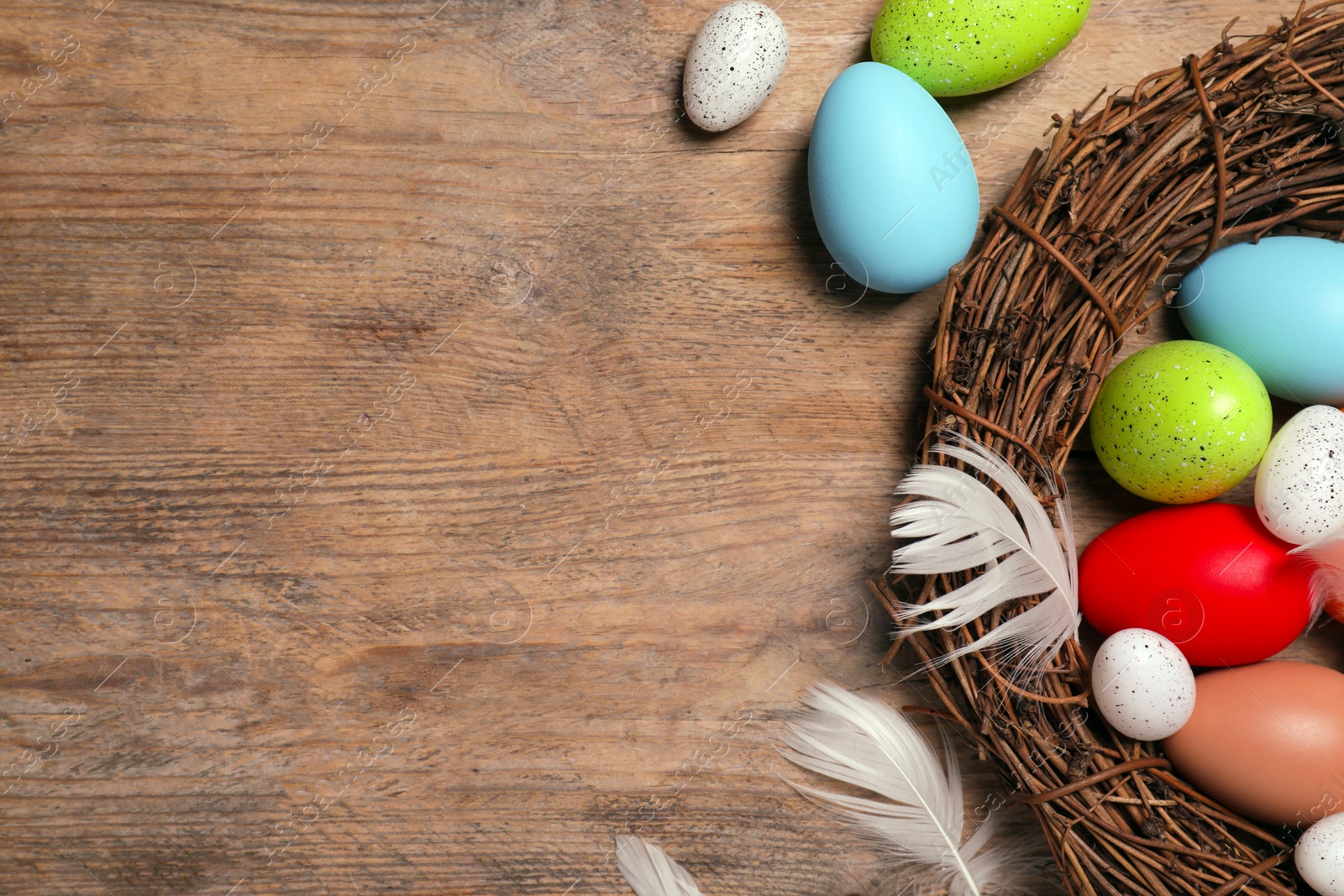 Photo of Flat lay composition with festively decorated Easter eggs and feathers on wooden table. Space for text