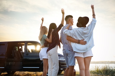 Photo of Group of friends near car outdoors. Summer trip