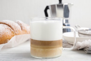 Photo of Delicious latte macchiato and croissant on white wooden table